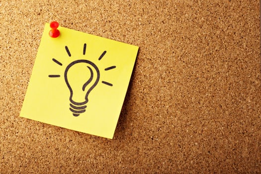 light bulb on a sticky note that is pinned to a bulletin board