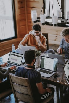 Men sitting around a table working on laptops