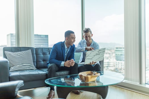 Two men smiling and looking at a laptop