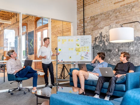 Man explaining words on a white board to group of men.
