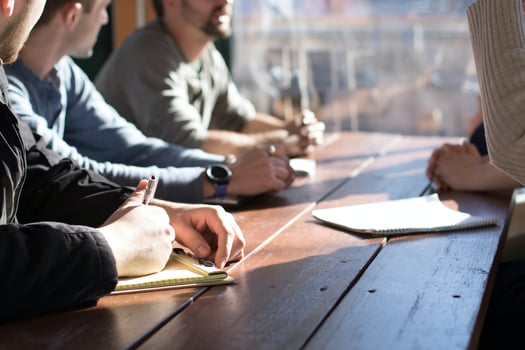 People sitting at a table taking notes.