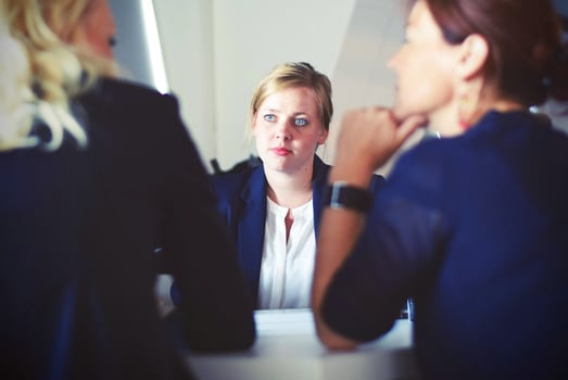 Woman sitting at desk in front of two other women