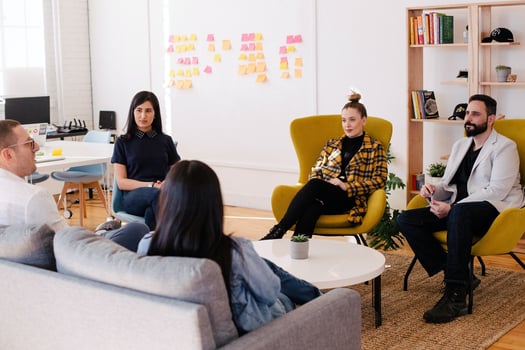 People sitting around a coffee table in a meeting.