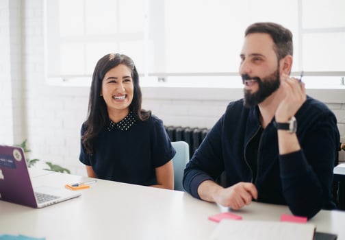 Man and woman sitting at a table laughing.